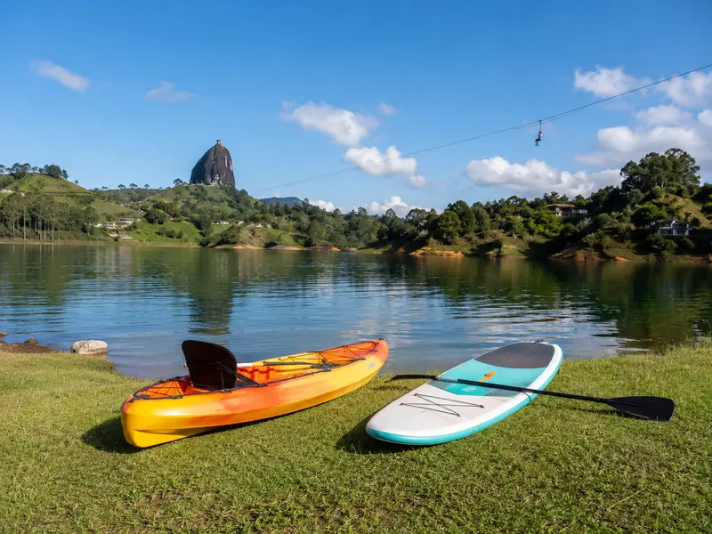 Kayak and paddleboard on the grassy Guatapé lakeshore with the zip line far across the water