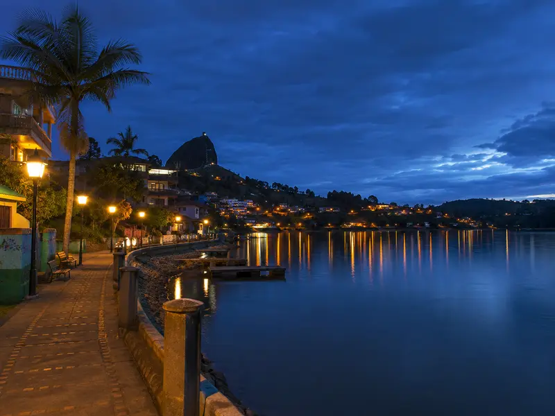 Guatapé lakefront malecón at blue hour with town lights reflecting on the water