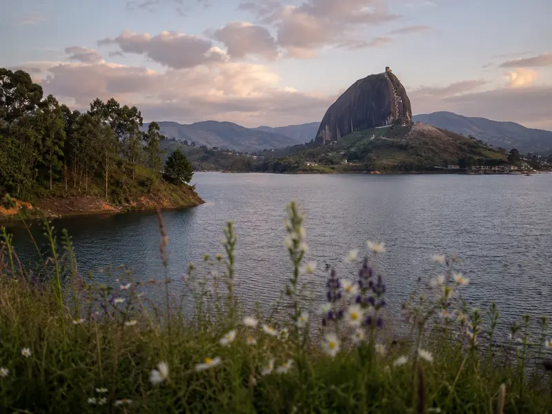 El Peñol Rock seen from a quiet wildflower hillside across the Guatapé reservoir